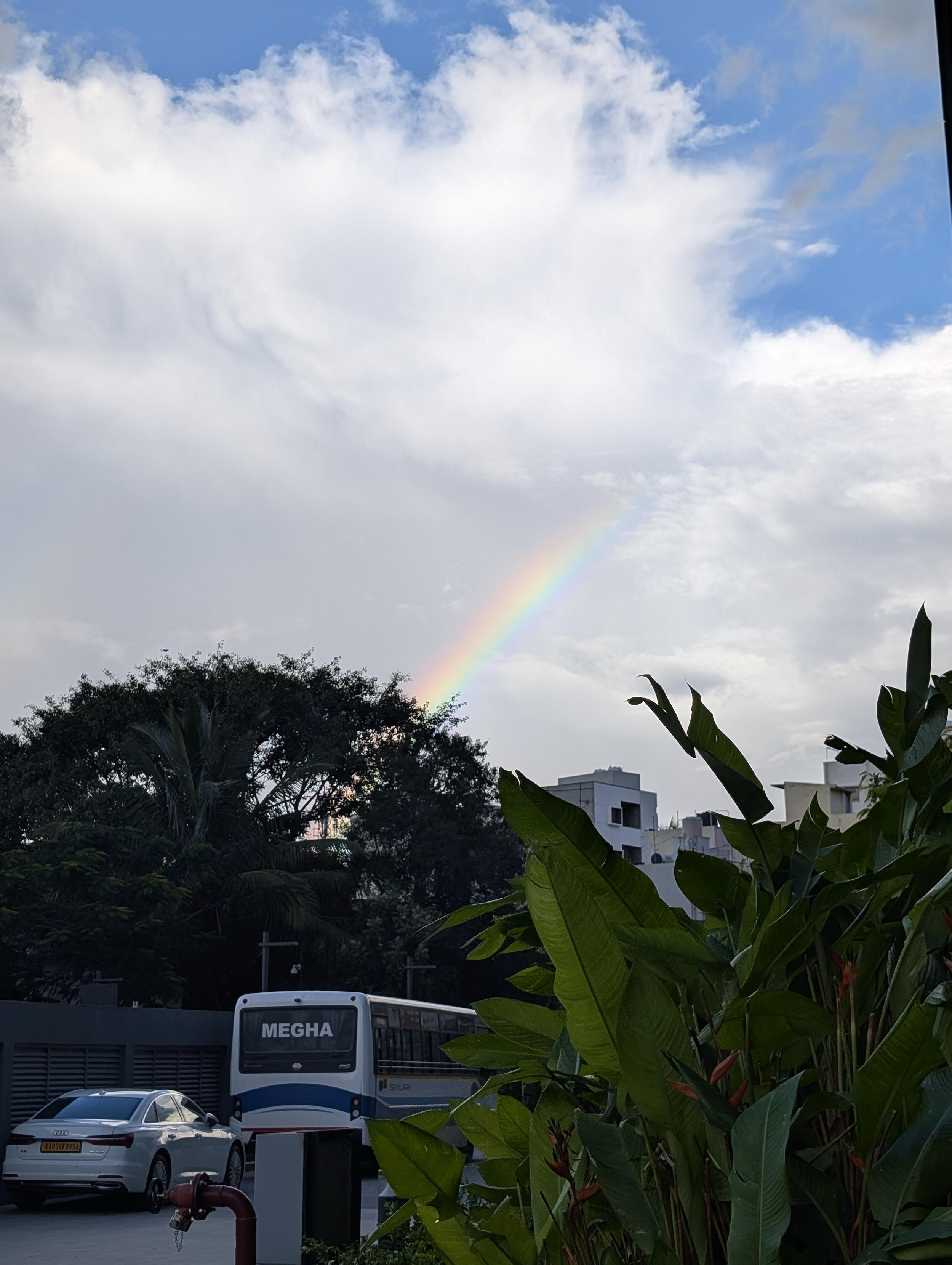 A cloudy blue sky with a rainbow across it